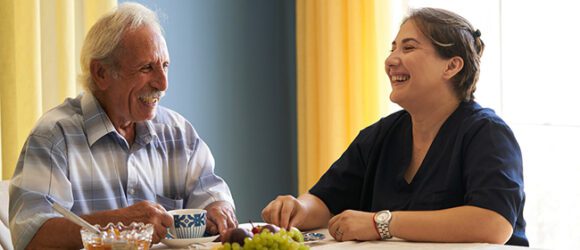 Professionele behulpzame verzorger en een senior man tijdens het thuisbezoek